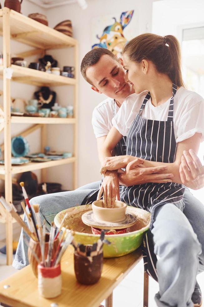 com o namorado ou marido. jovem ceramista feminina trabalha em ambientes fechados com produtos de argila feitos à mão. concepção de cerâmica foto