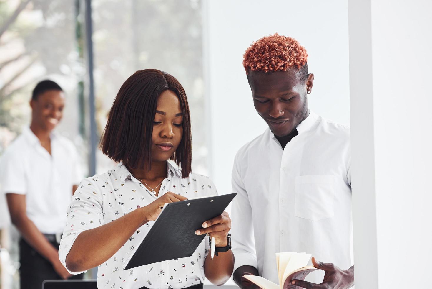 segurando o bloco de notas. grupo de empresários afro-americanos trabalhando juntos no escritório foto