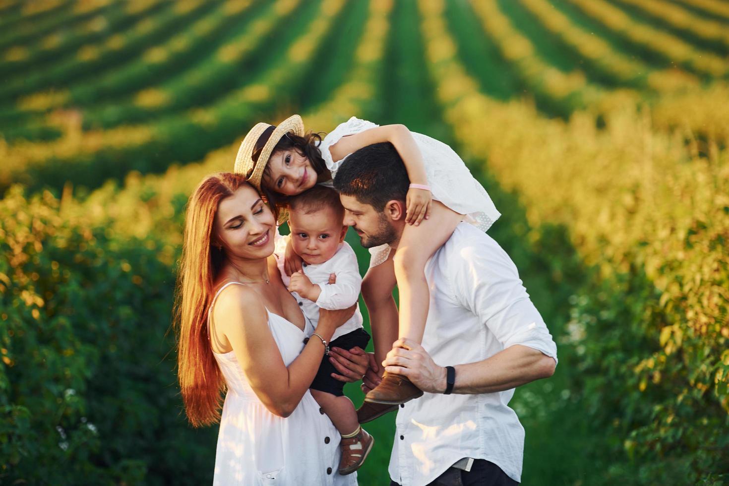 no campo agrícola. pai, mãe com filha e filho passando o tempo livre ao ar livre no dia ensolarado do verão foto