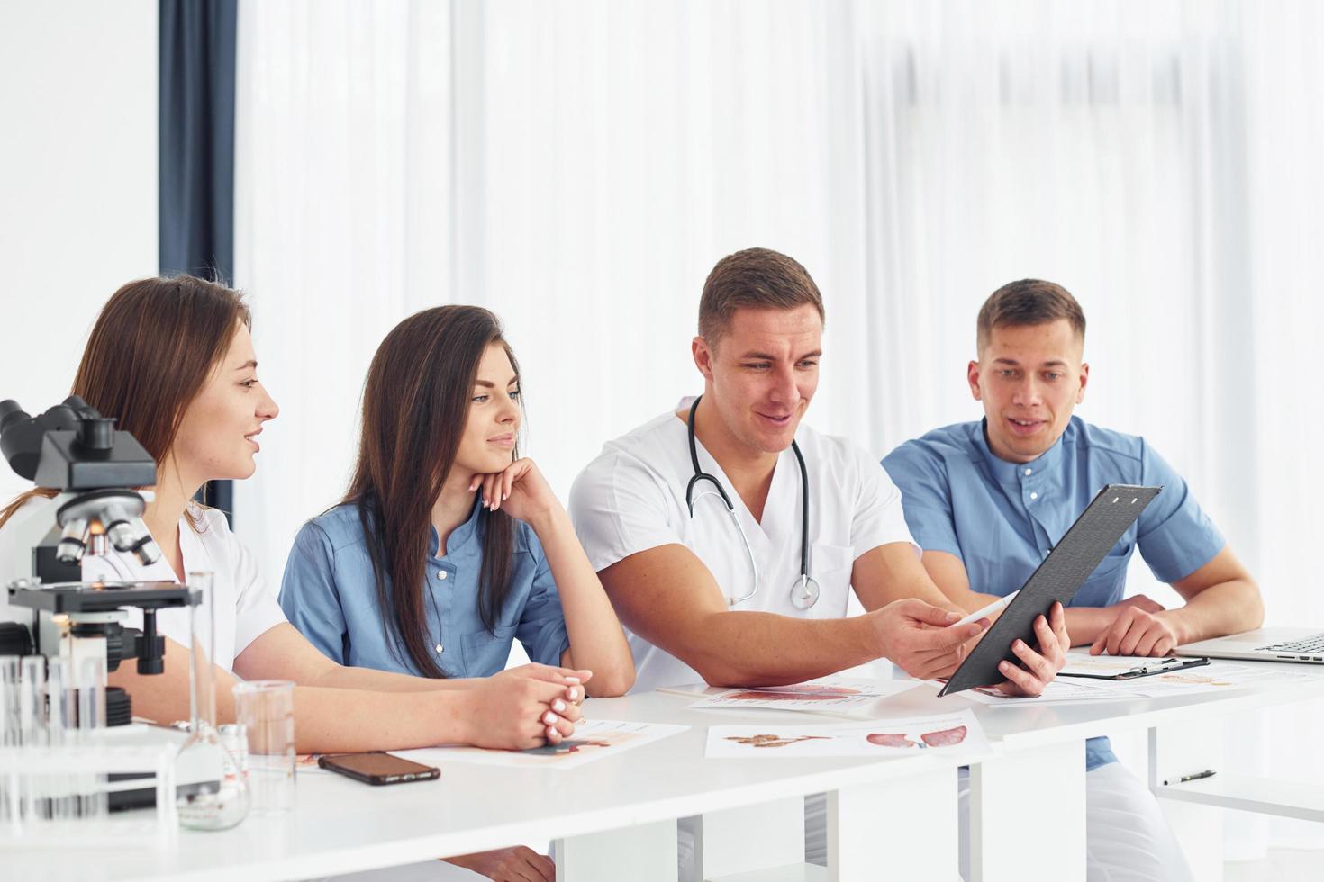 sentado à mesa. grupo de jovens médicos está trabalhando juntos no escritório moderno foto