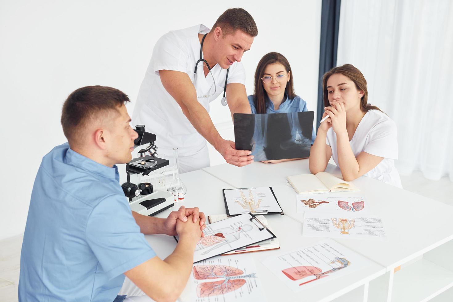 homem com microscópio. grupo de jovens médicos está trabalhando juntos no escritório moderno foto