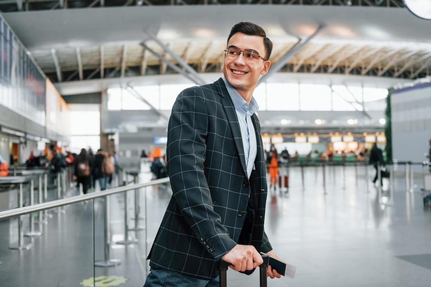 com bagagem. jovem empresário em roupas formais está no aeroporto durante o dia foto