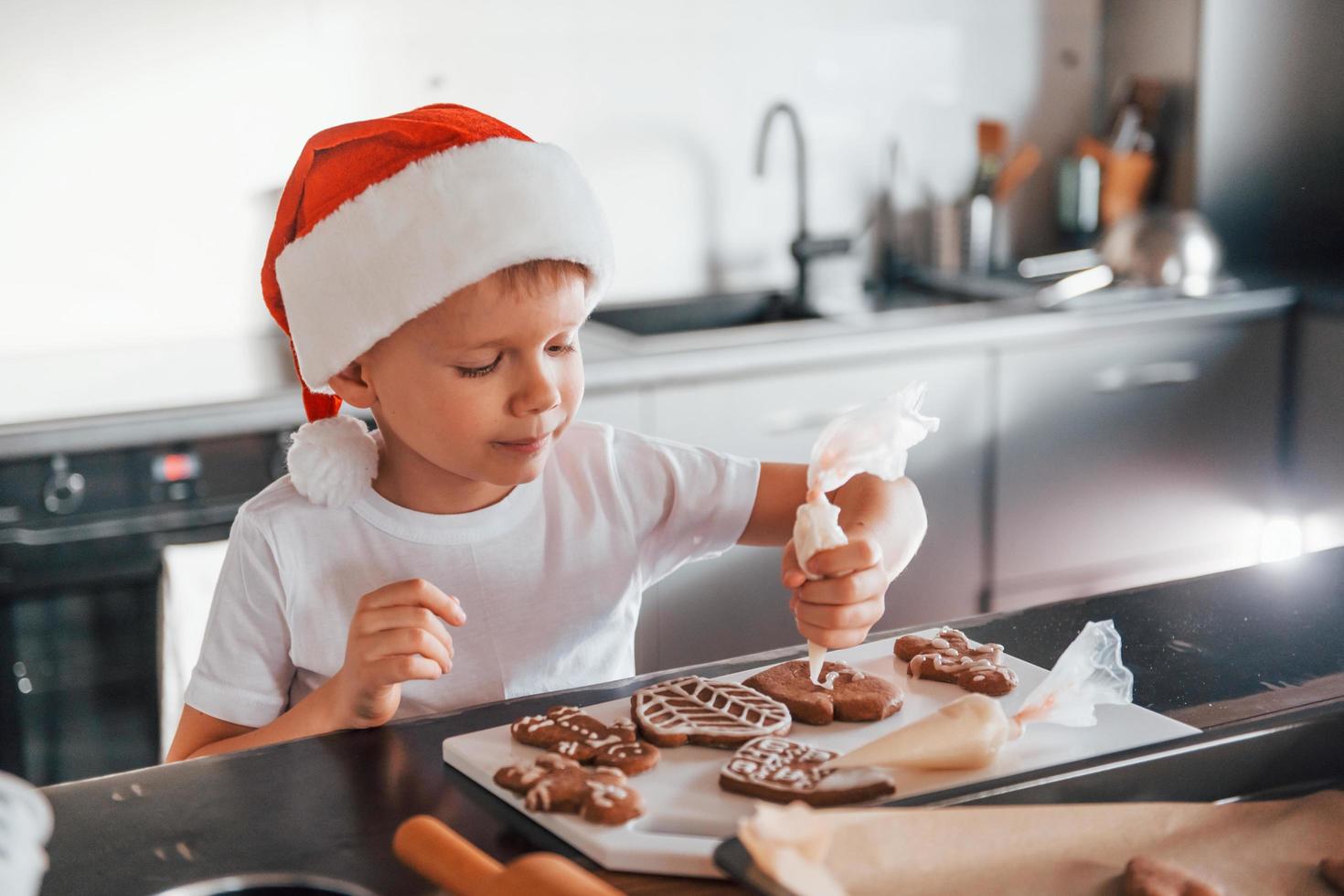 garotinho preparando biscoitos de natal na cozinha foto