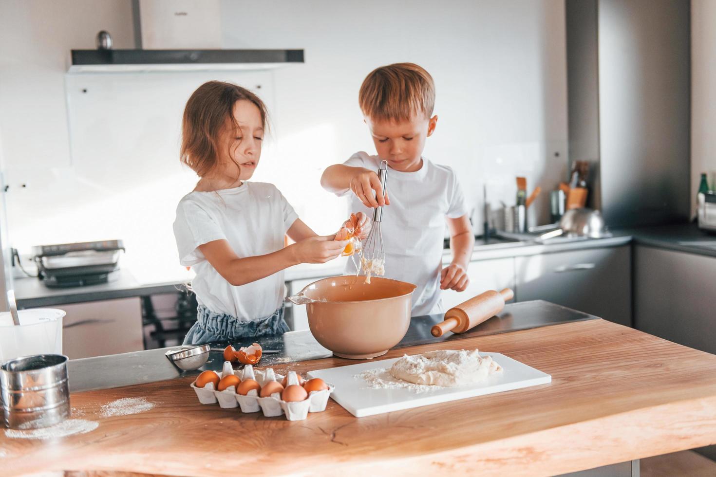 trabalhando com massa. menino e menina preparando biscoitos de natal na cozinha foto