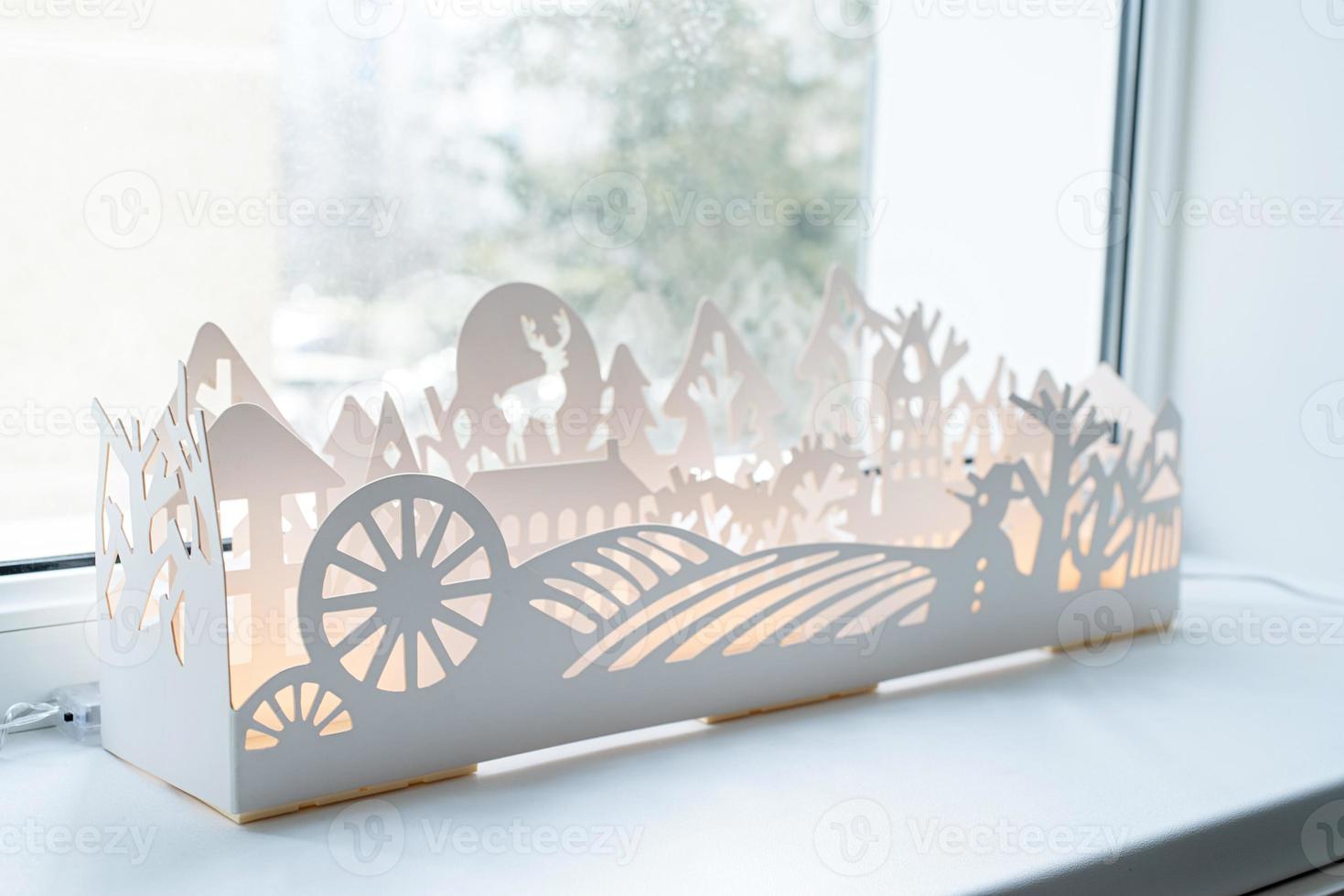 papel branco bonito ou decoração de inverno de plástico com luzes no peitoril da janela foto