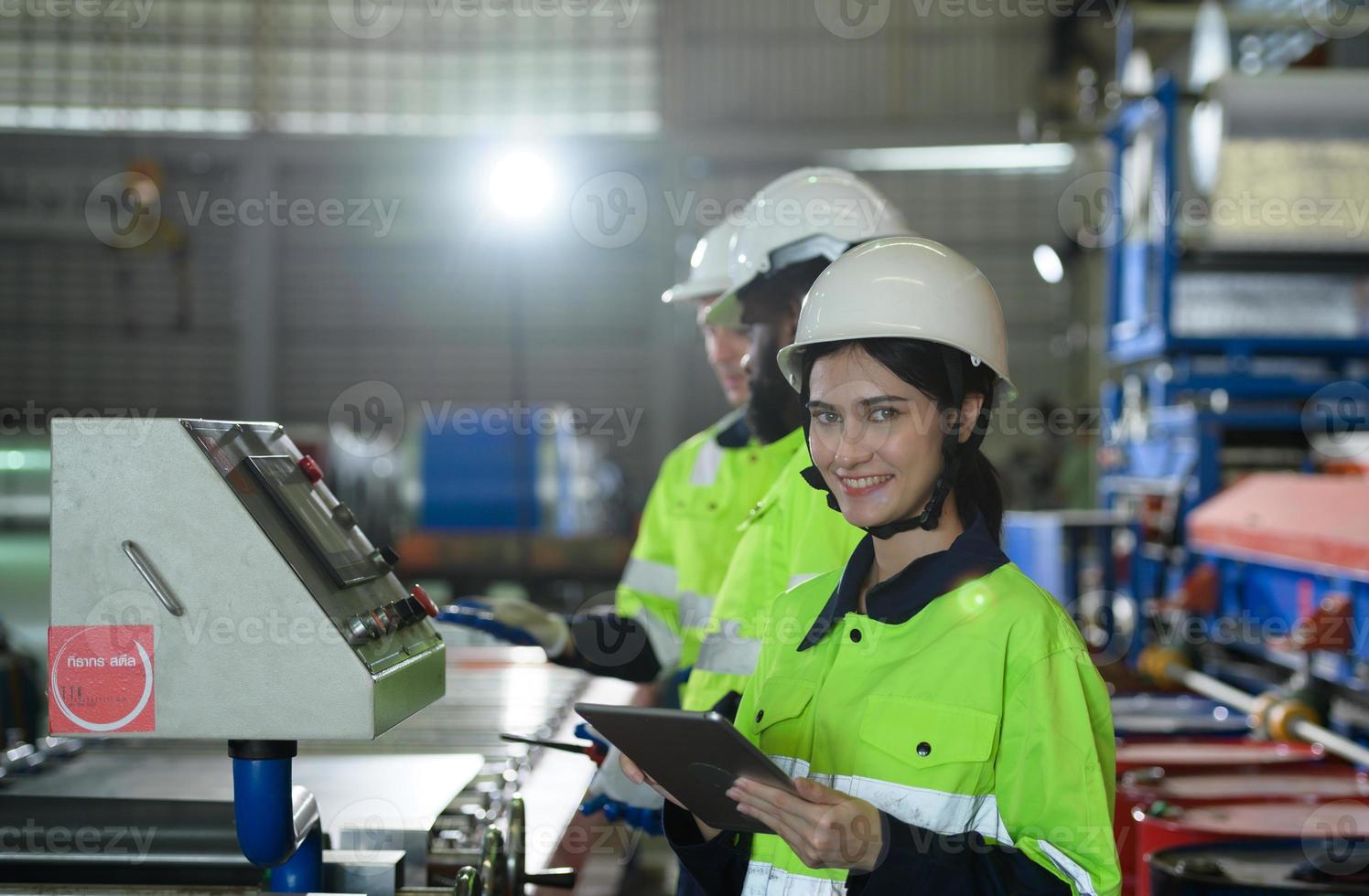 jovem engenheira aprendendo a operar máquinas em uma fábrica com engenheiros veteranos foto