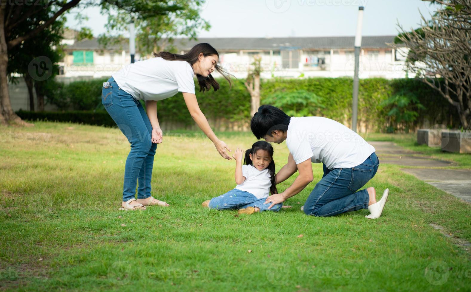 uma garotinha ficou levemente ferida enquanto brincava com seus pais, confortando-a ao seu lado. foto