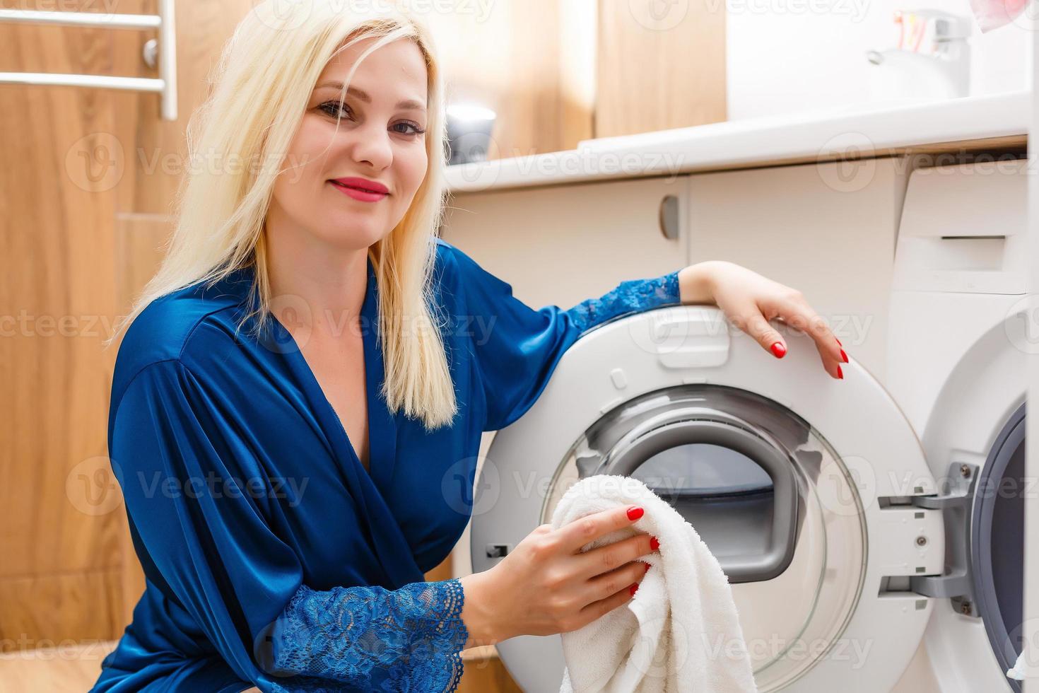 uma dona de casa feliz na lavanderia com máquina de lavar foto