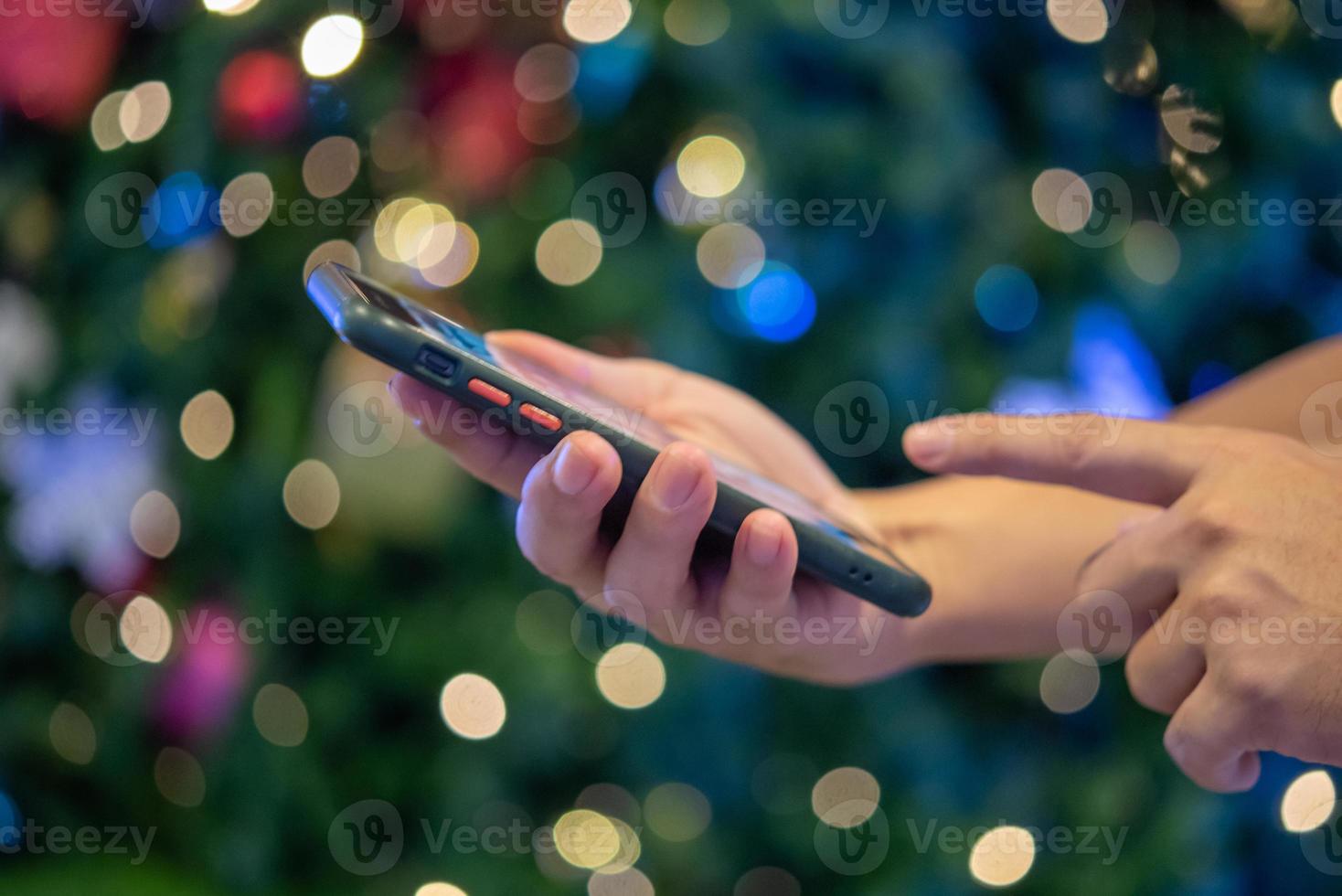 mãos masculinas usando smartphone à noite na cidade com bokeh de fundo. foto