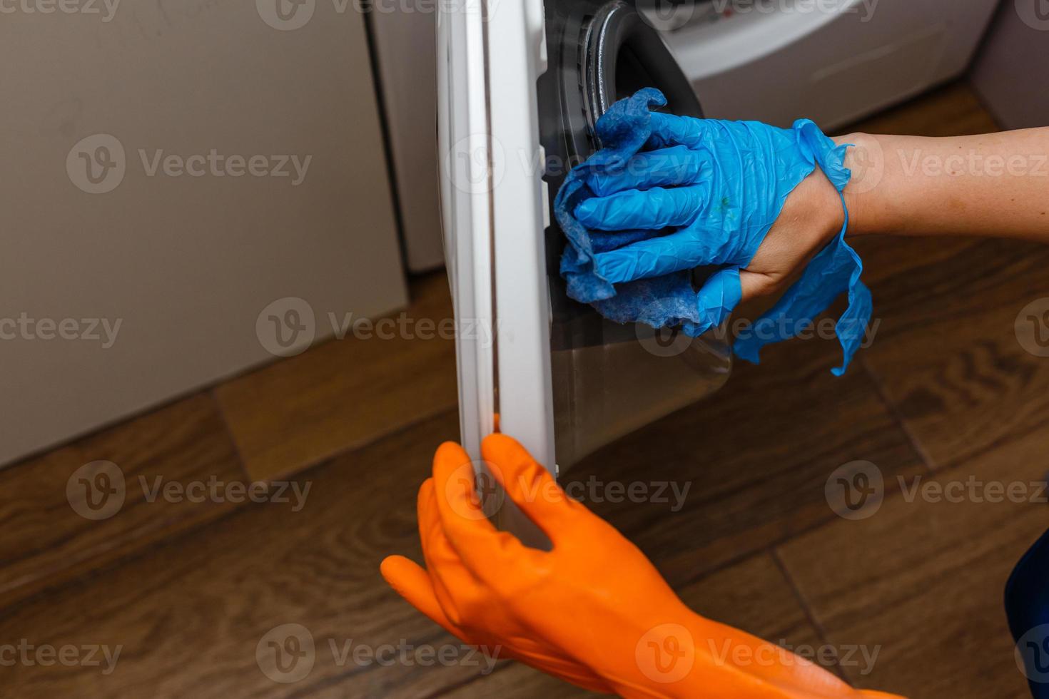 mão na luva rasgada limpando a máquina de lavar. limpeza regular. empregada limpa a casa. foto