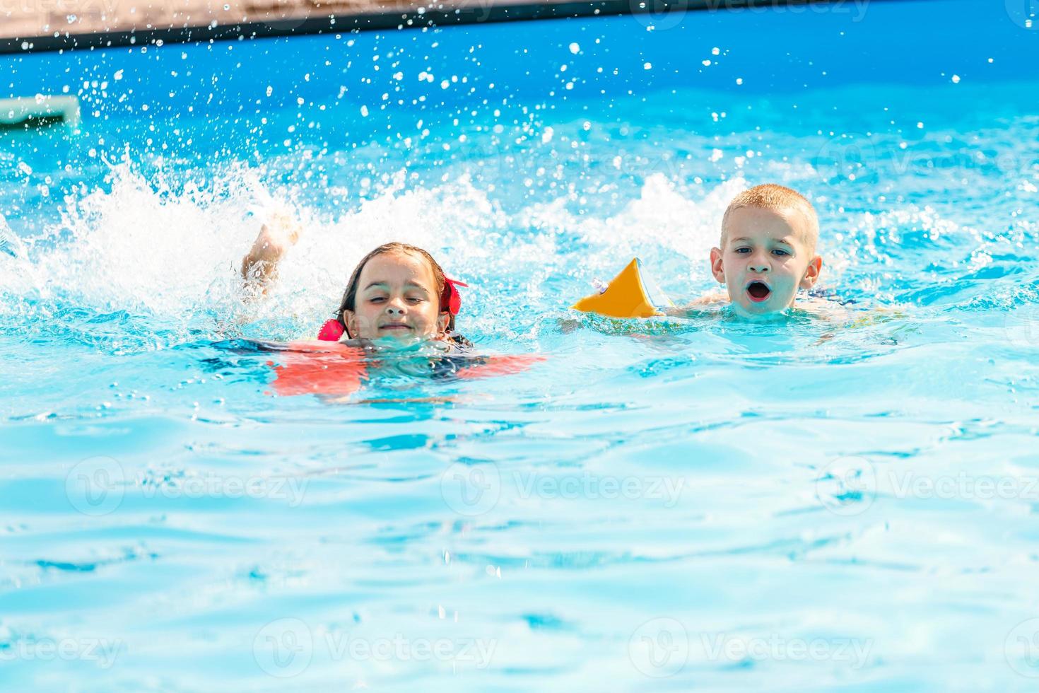 menino sorridente e menina nadando na piscina do parque aquático foto