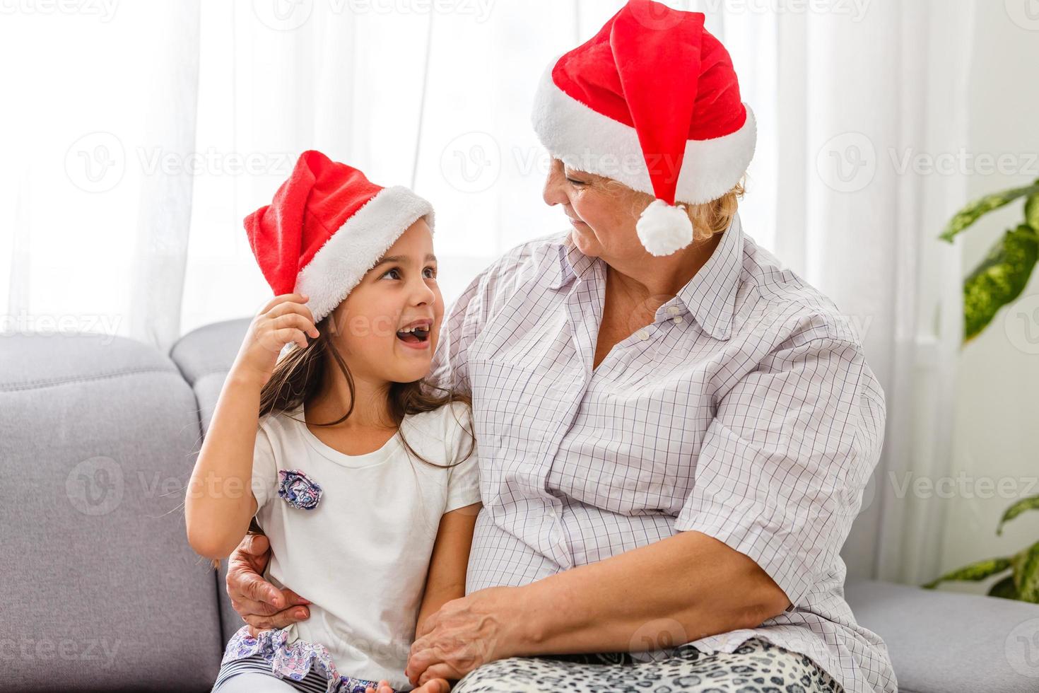 retrato da avó com menina adolescente em chapéus de Papai Noel se preparando para o natal em casa foto