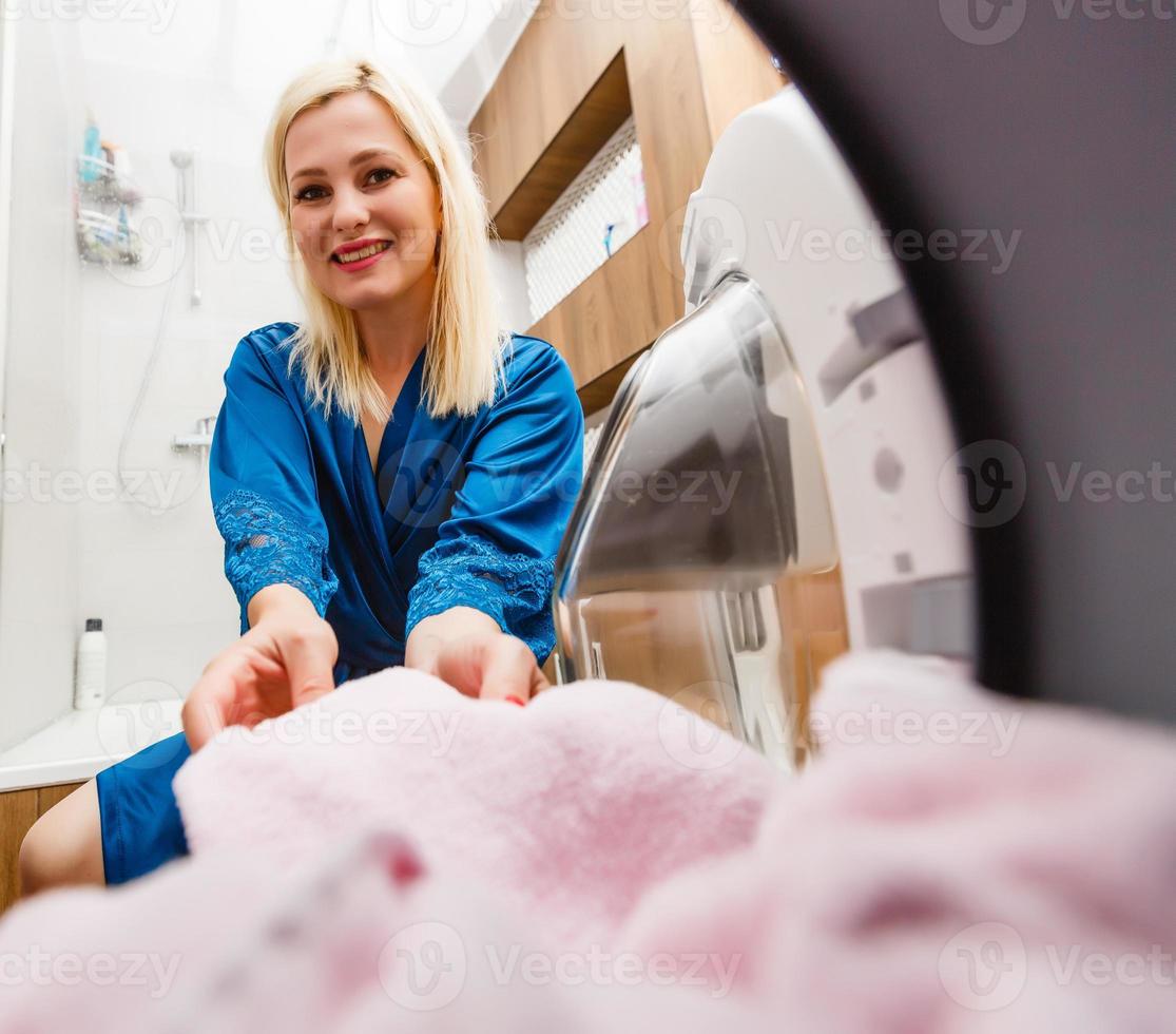 uma dona de casa feliz na lavanderia com máquina de lavar foto