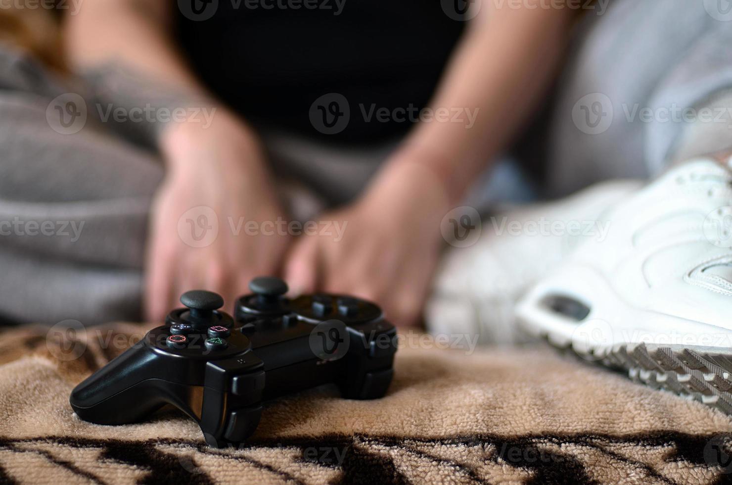 controlador de jogo preto moderno nas mãos de uma jovem sentada foto