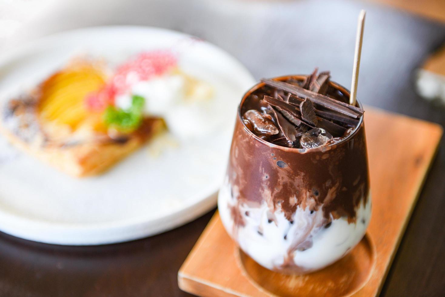 bebida de cacau e saboroso milk-shake de chocolate com cacau gelado em vidro sobre fundo de madeira foto