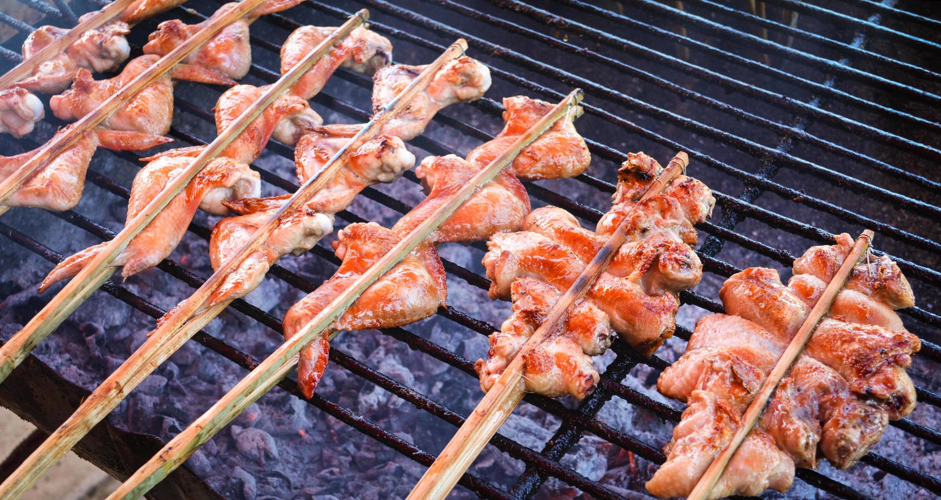 comida tailandesa grelhada asa de frango com vara de bambu na grelha foto