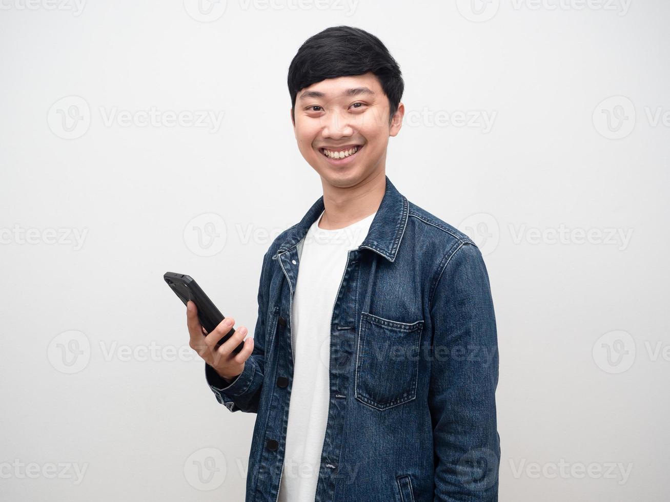 homem alegre camisa jeans sorriso segurando smartphone foto