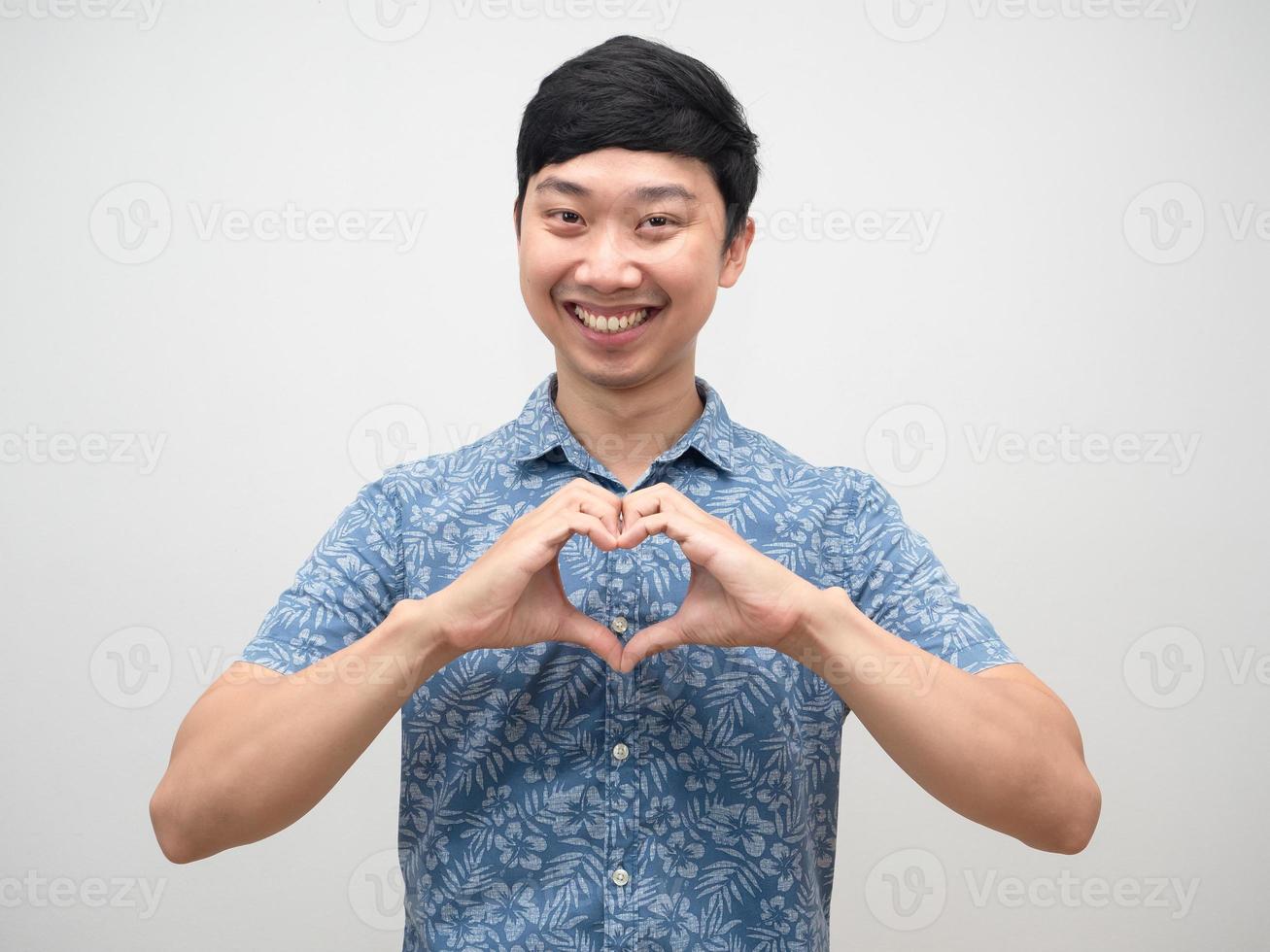 homem positivo camisa azul sorrindo faça coração de mão isolado foto