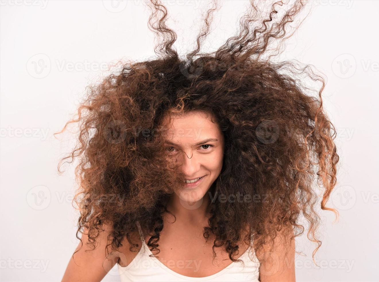 garota bonita, atraente, bem cuidada, alegre, alegre, de cabelos ondulados, usando secador elétrico foto