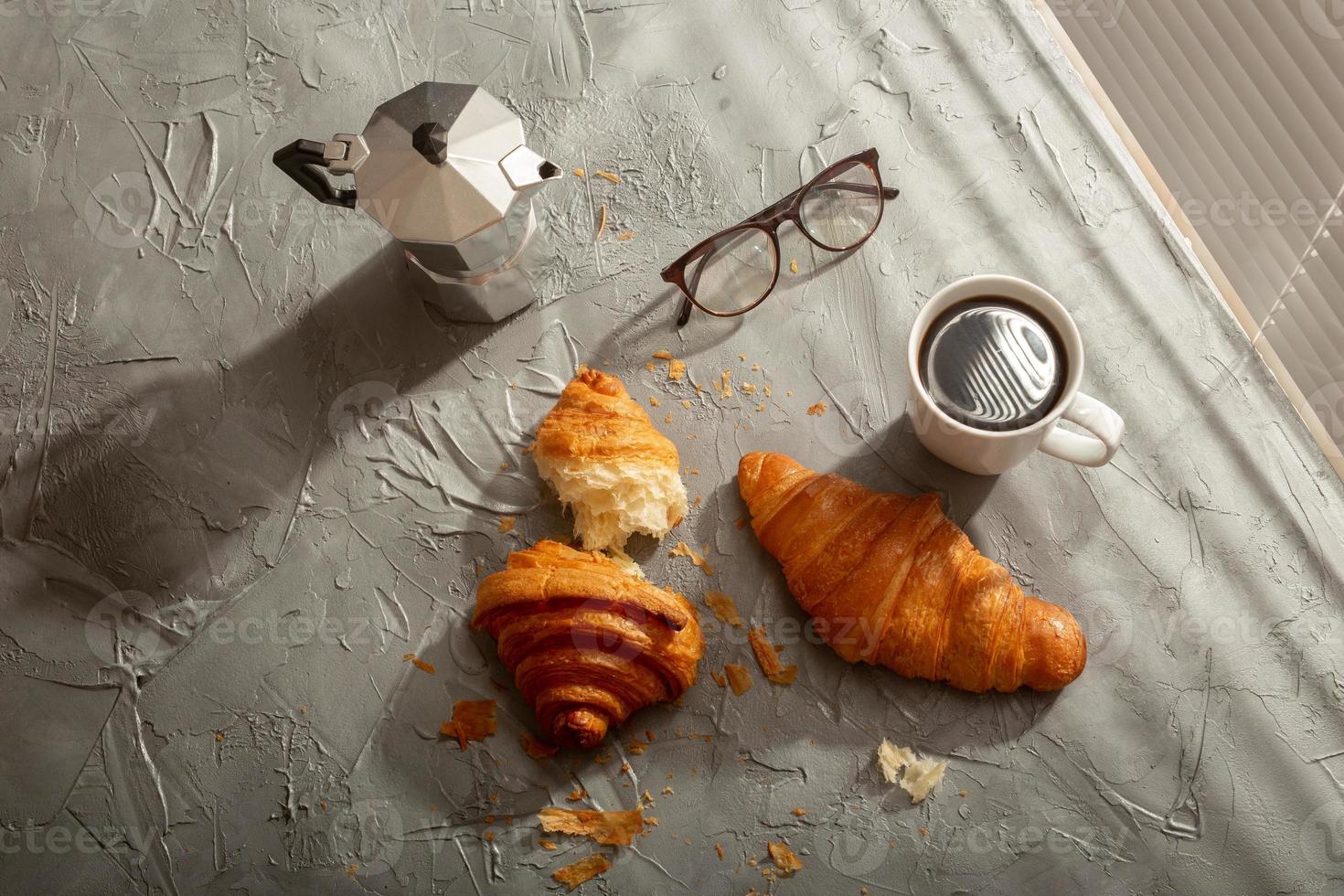 café da manhã com croissant na tábua e café preto. refeição matinal e conceito de café da manhã. vista do topo. foto