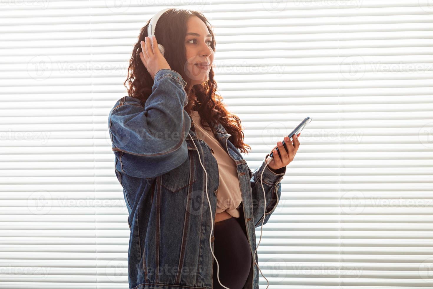 bela jovem pacífica grávida ouve música clássica agradável usando smartphone e fones de ouvido. conceito de atitude positiva antes do parto foto