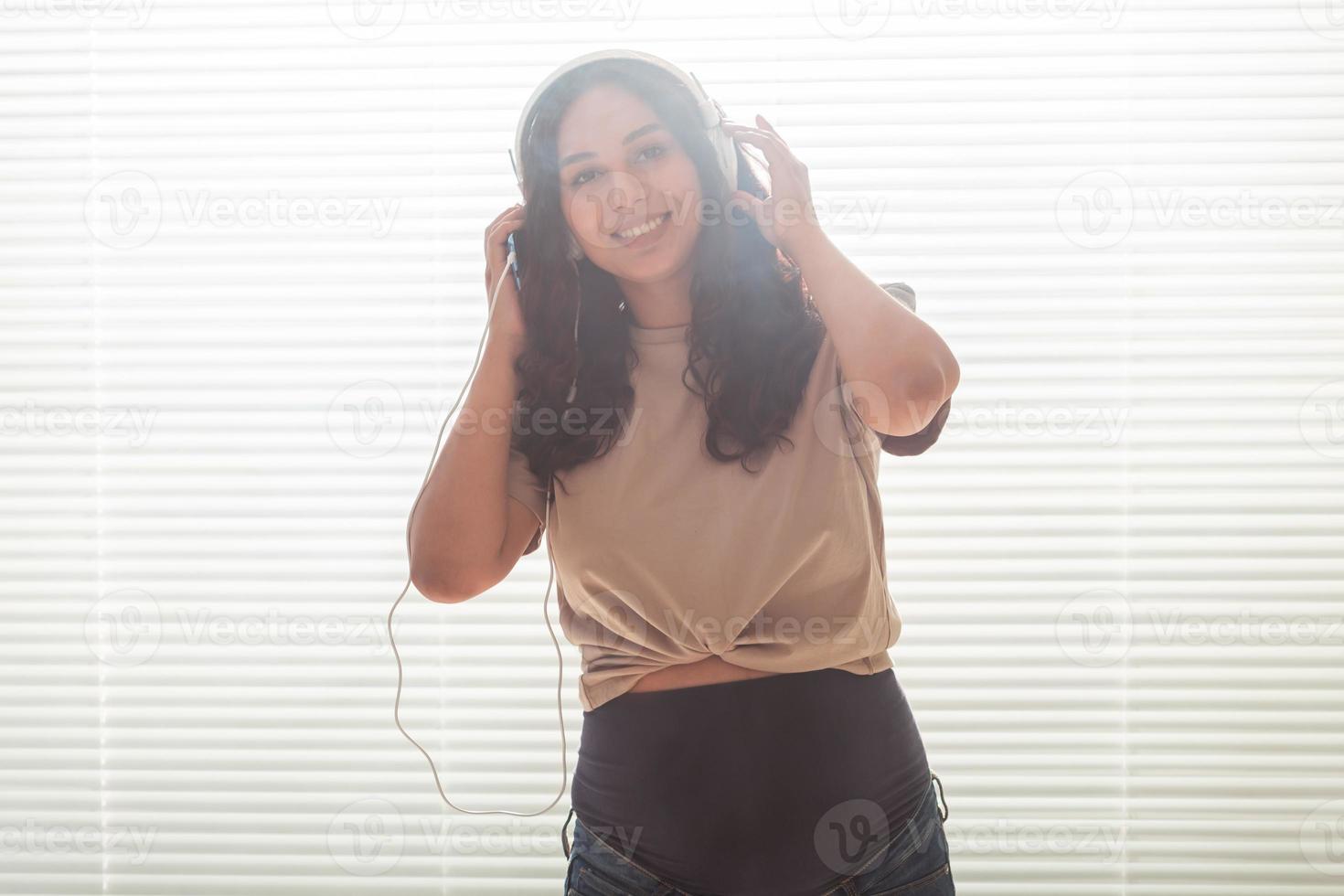 bela jovem pacífica grávida ouve música clássica agradável usando smartphone e fones de ouvido. conceito de atitude positiva antes do parto foto