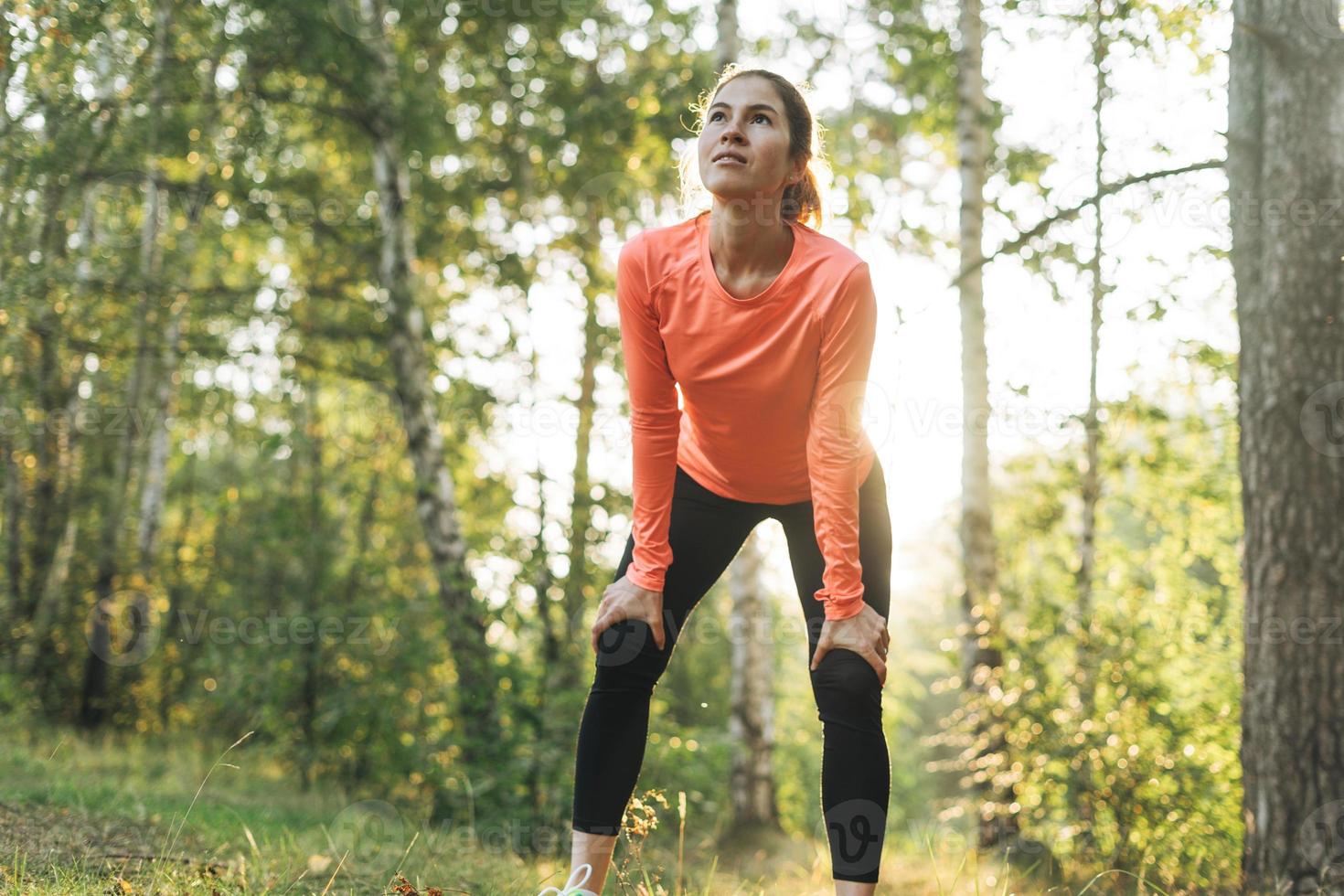 jovem morena magro em roupas esportivas correndo na floresta na hora dourada do nascer do sol. saúde e bem-estar, estilo de vida fitness foto