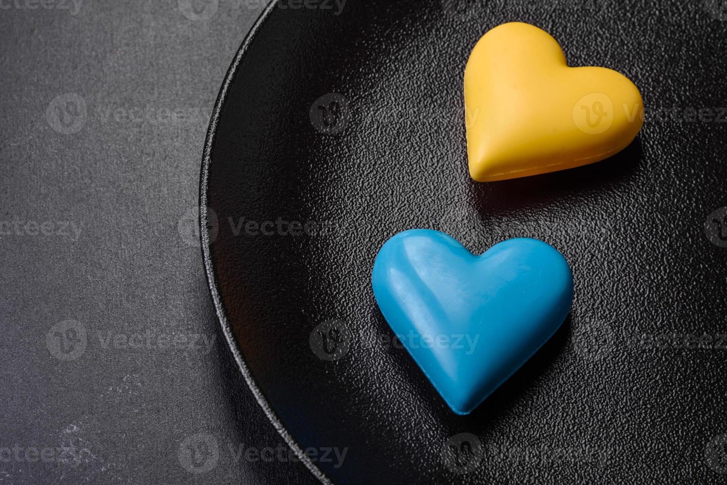 corações de chocolate nas cores da bandeira ucraniana em uma placa de cerâmica preta foto