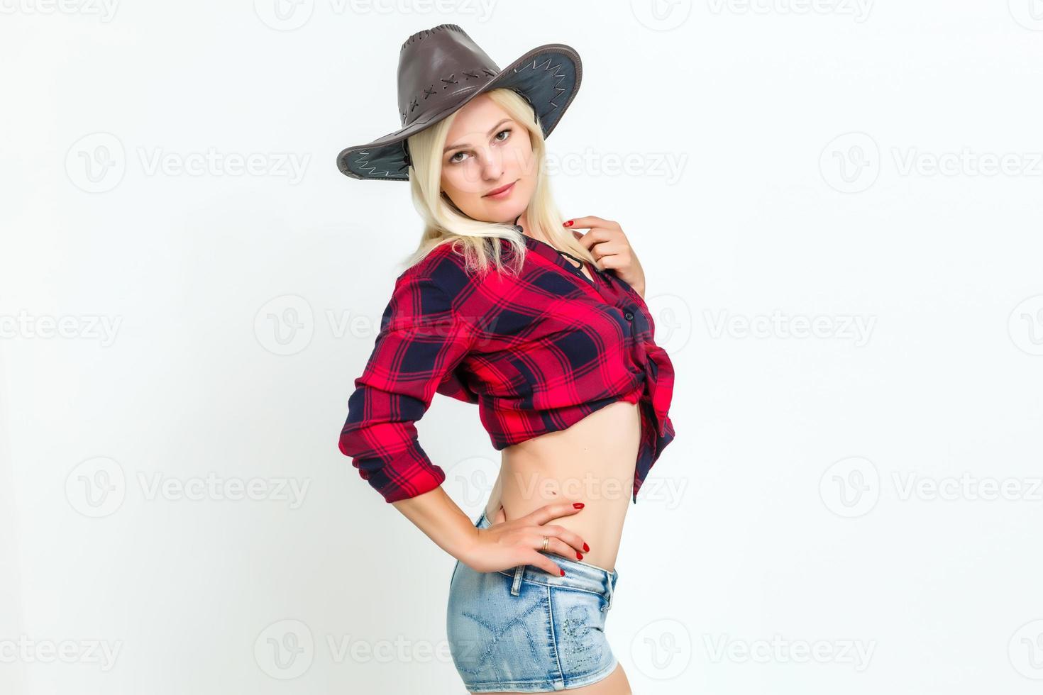 a mulher loira sexy com um chapéu de cowboy em um fundo branco foto