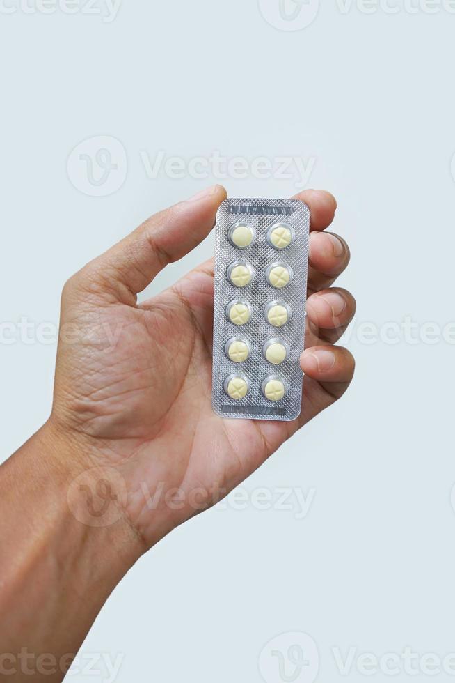 mão de homem asiático segurando um pacote de pílulas amarelas isoladas no fundo branco. foto