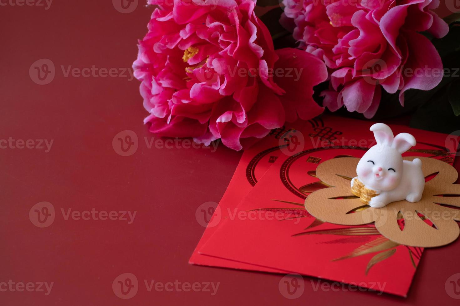 ano novo chinês do conceito de festival de coelho. tangerina, envelopes vermelhos, coelho e lingote de ouro decorado com flor de ameixa sobre fundo vermelho. foto