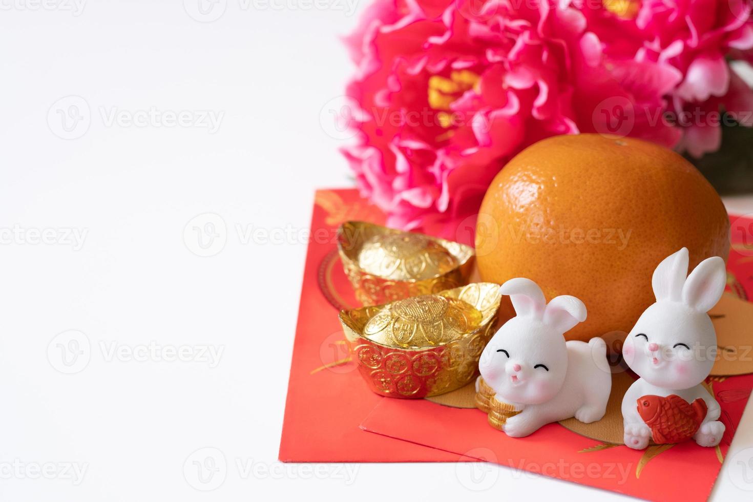 ano novo chinês do conceito de festival de coelho. laranja, envelopes vermelhos, dois coelhos e lingote de ouro decorado com flor de ameixa em fundo branco. foto