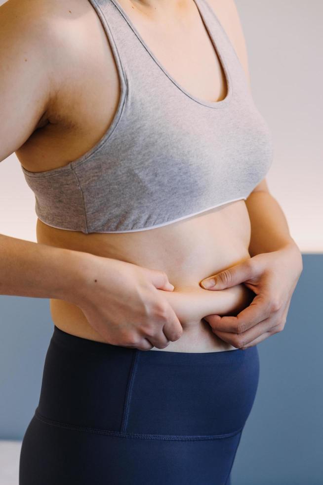 linda mulher gorda com fita métrica ela usa a mão para espremer o excesso de gordura que está isolado em um fundo branco. ela quer perder peso, o conceito de cirurgia e quebrar a gordura sob o foto