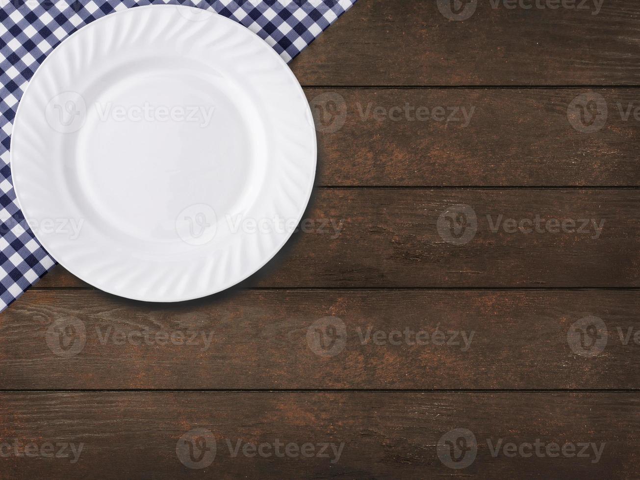 toalha de mesa azul na gaiola e prato vazio no fundo da mesa de madeira foto