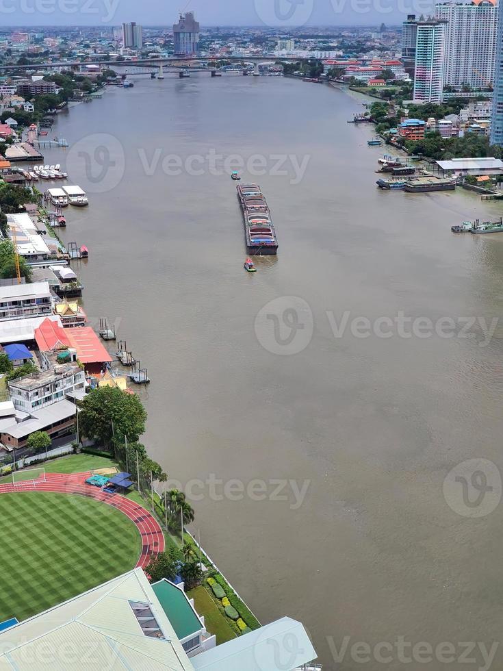 vista aérea de um pequeno rebocador rebocando uma grande barcaça de areia, barco de areia carregando carga de areia no rio chao phraya em bangkok, tailândia foto