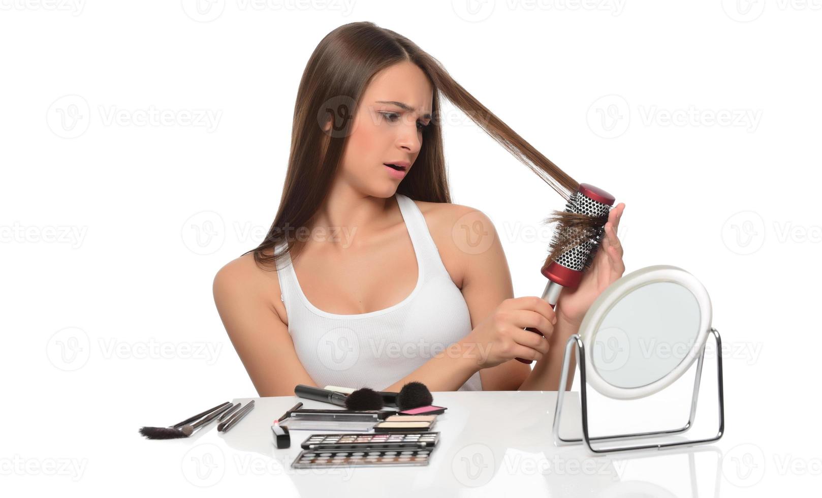jovem mulher bonita olha no espelho escova cabelo morena longo e saudável foto
