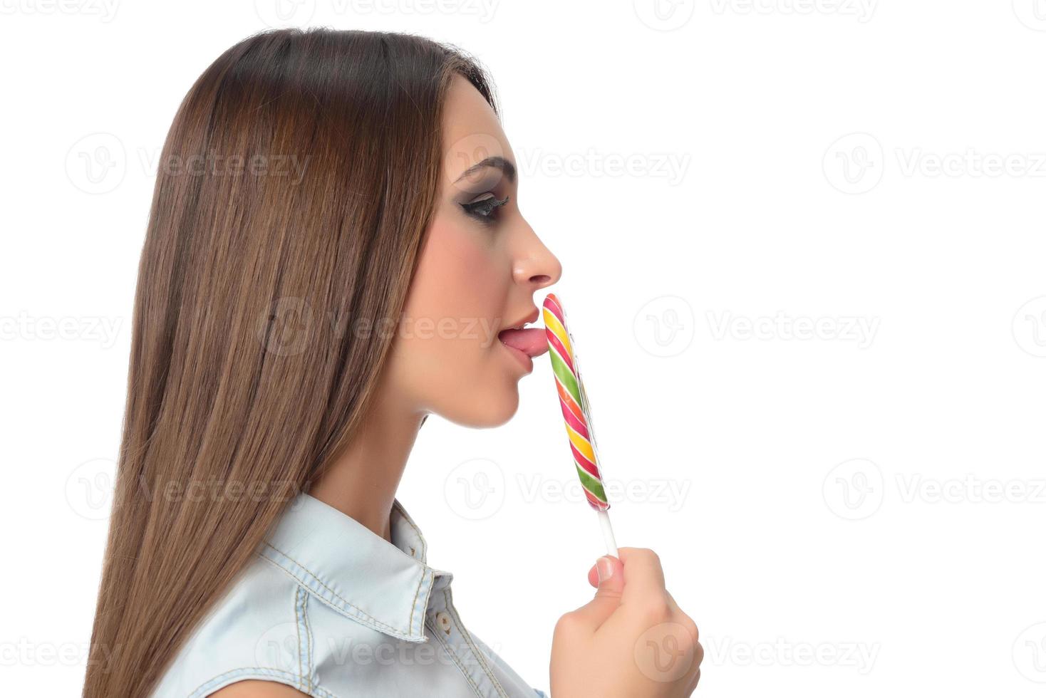 mulher lambendo doces. modelo feminino comendo delicioso pirulito de confeitaria com expressão de surpresa. tiro de estúdio isolado fundo branco foto