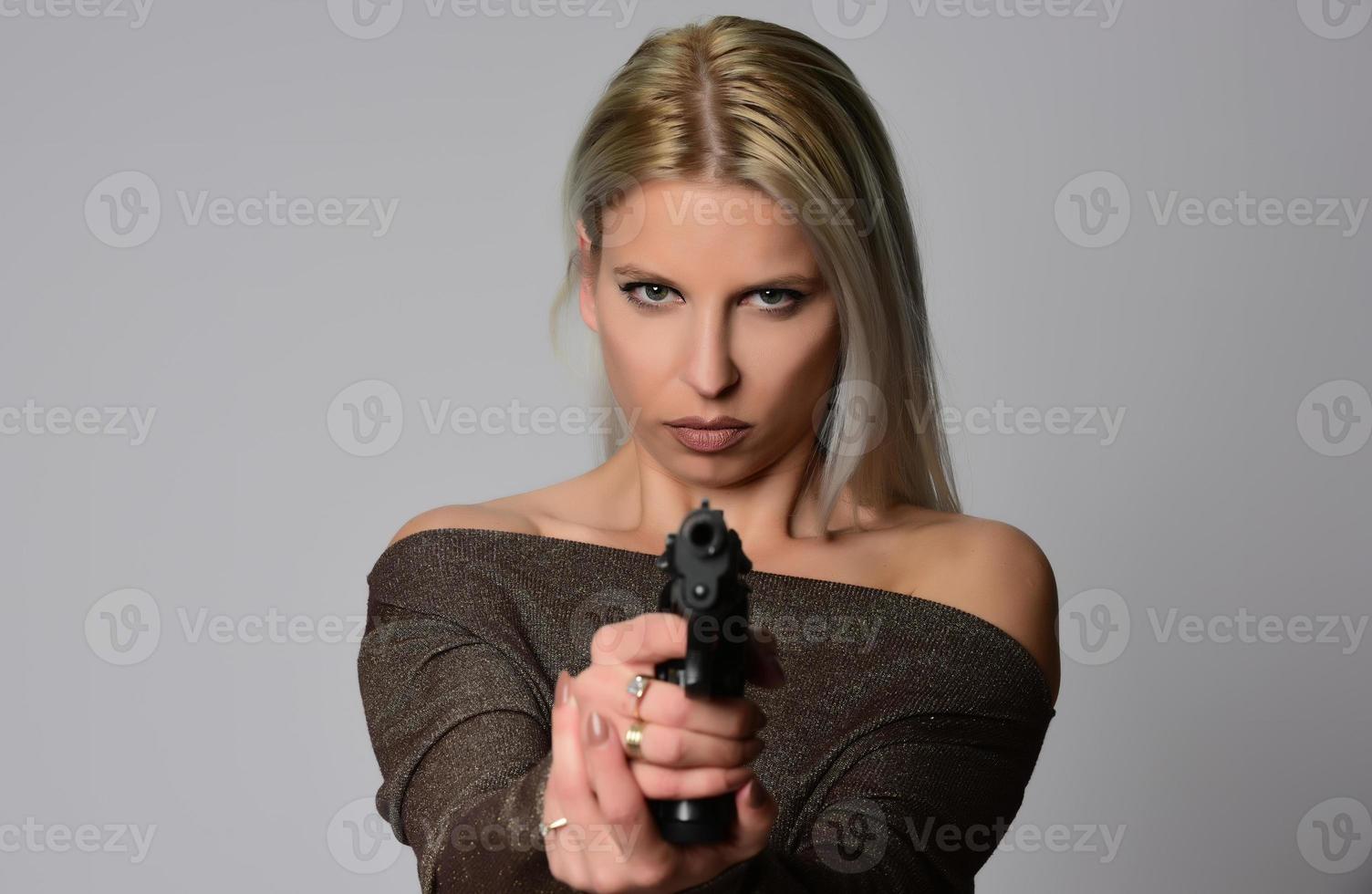 jovem bela mulher loira sexy segurando a arma na mão foto