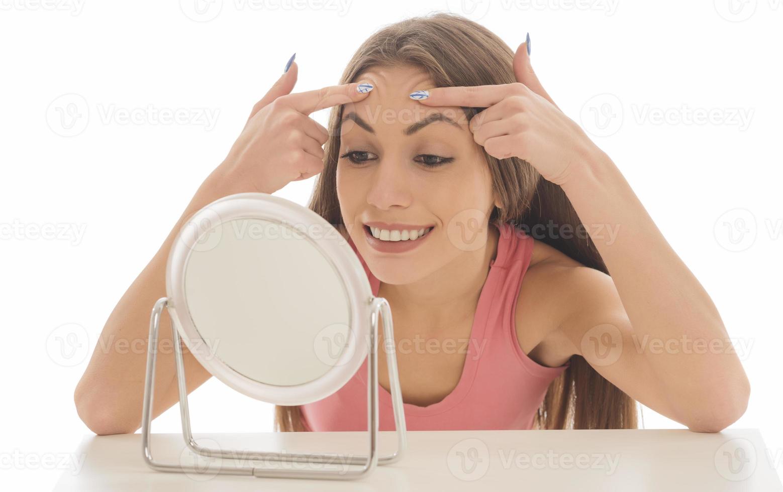 linda mulher sentada na frente de um espelho. rosto de uma mulher saudável aplicando creme e maquiagem. anúncio de creme para a pele, creme anti-rugas, rosto de bebê foto