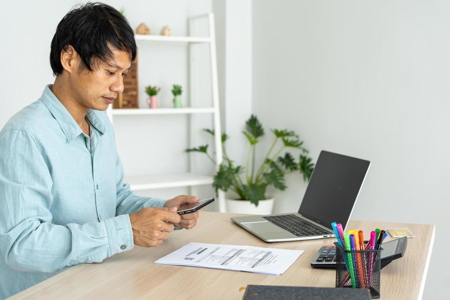 homem de negócios usa telefone para digitalizar código de barras ou códigos qr para pagar a fatura do cartão de crédito após receber a fatura do documento online. pagamento, receber, pagar eletricidade, pagamentos digitais sem dinheiro, tecnologia foto