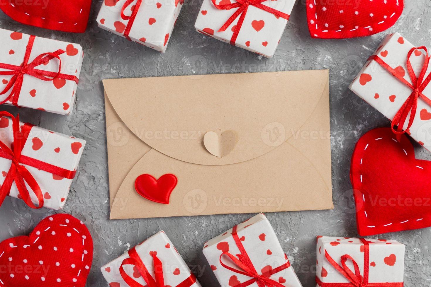 correio de envelope com coração vermelho e caixa de presente sobre fundo cinza de cimento. cartão de dia dos namorados, amor ou conceito de saudação de casamento foto