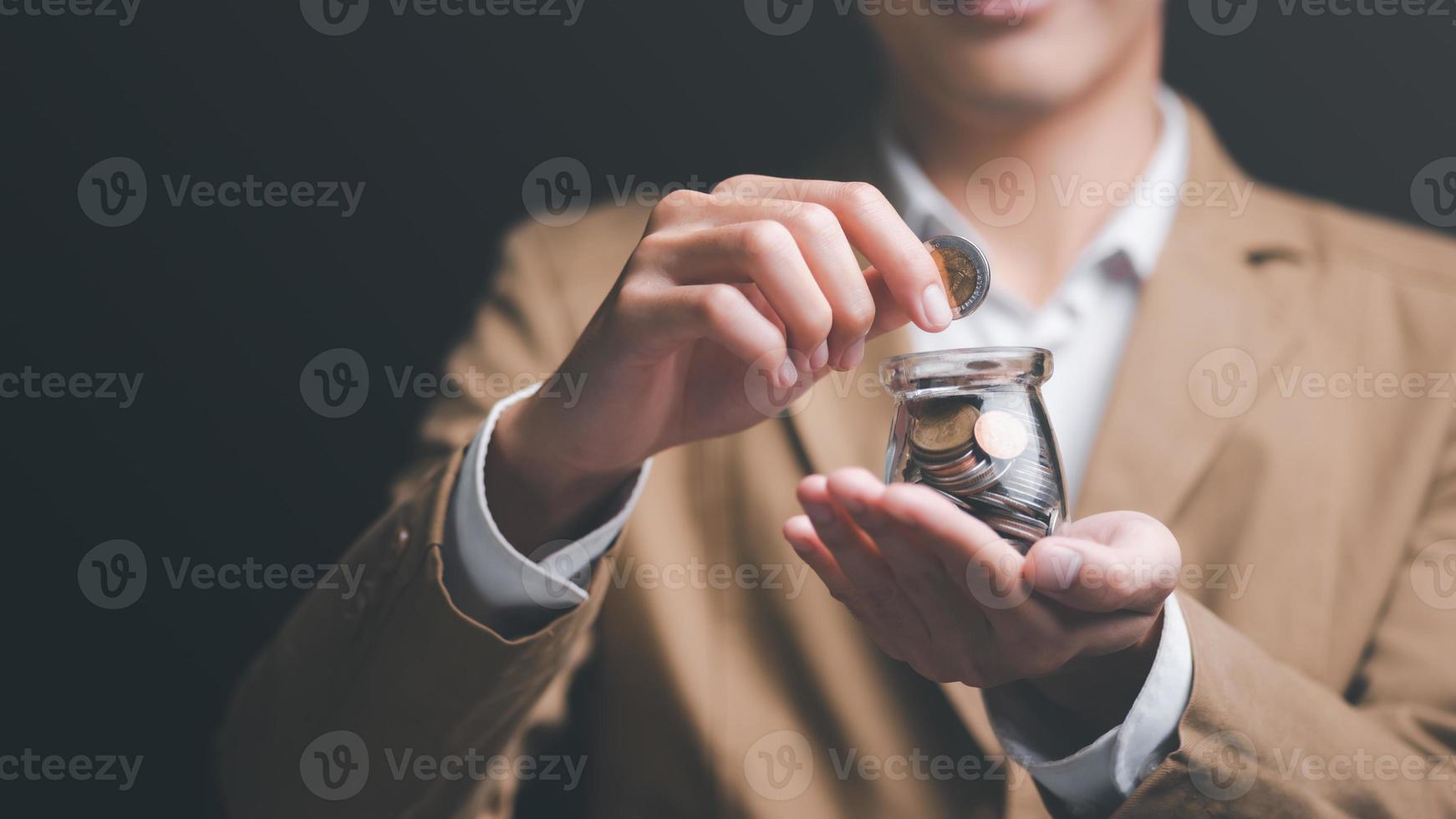 homem colocando moedas em uma jarra de vidro, finanças e serviços bancários, conceito de crescimento e economia de fundos, economizando dinheiro para o futuro, planejamento financeiro eficiente, economizando para a aposentadoria, proteção do seu dinheiro foto