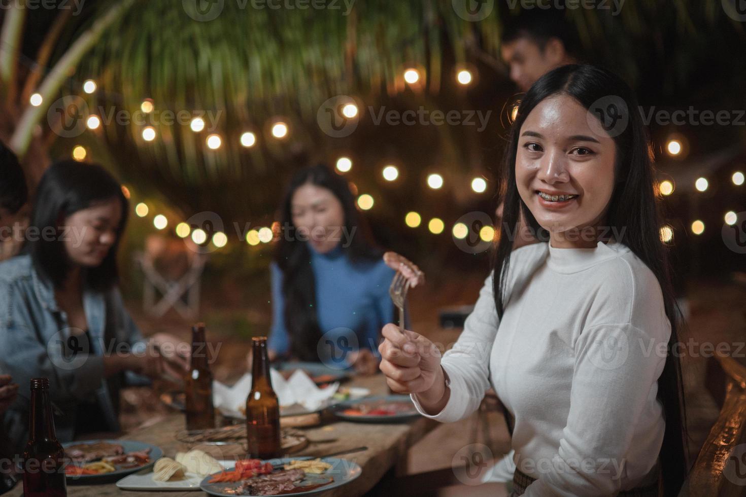 jovem asiática se exibindo comendo bife em uma festa foto