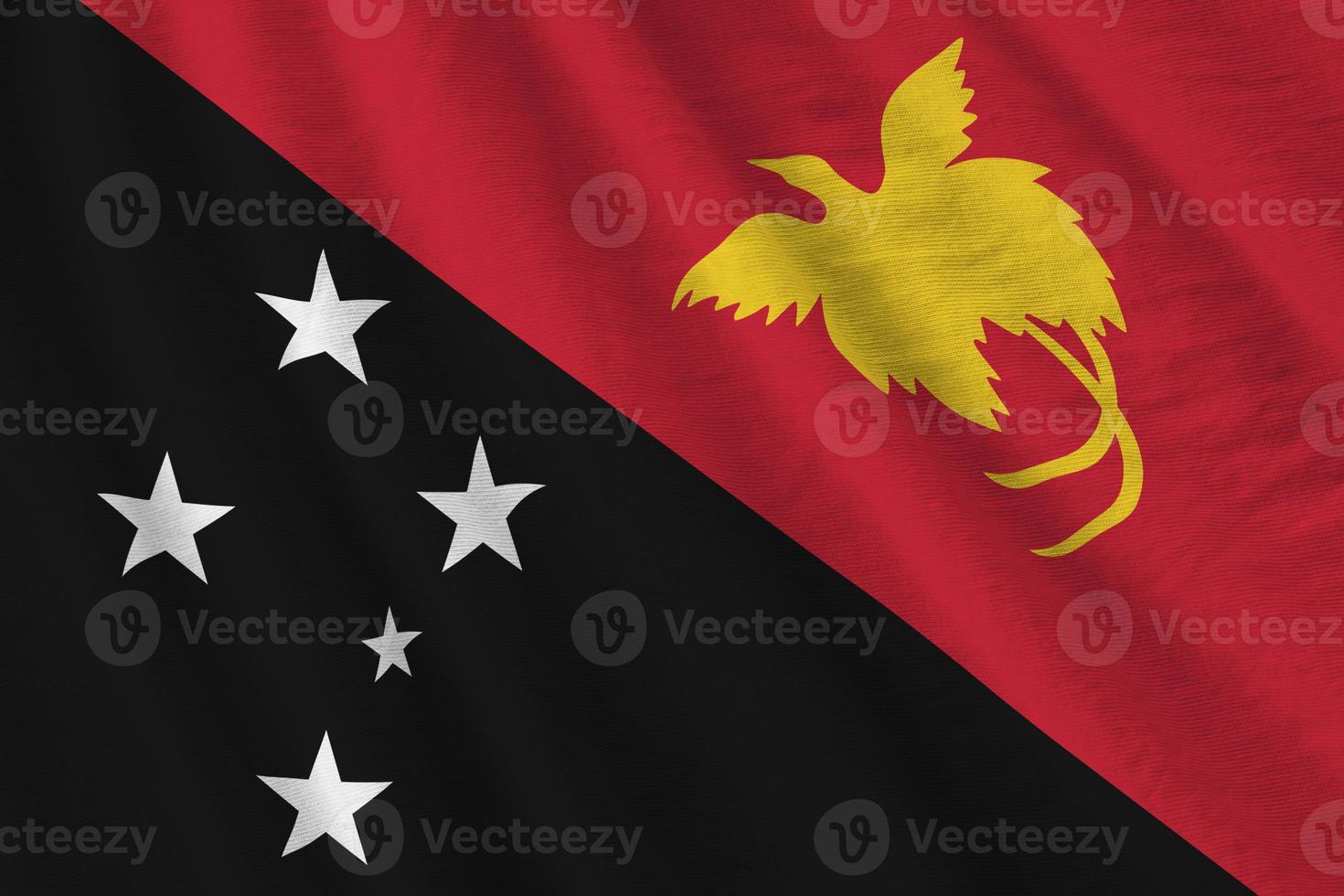 bandeira de papua nova guiné com grandes dobras acenando perto sob a luz do estúdio dentro de casa. os símbolos e cores oficiais no banner foto
