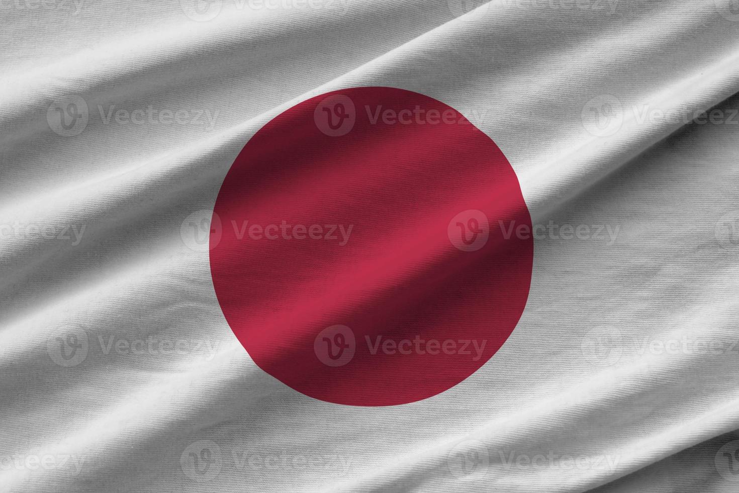 bandeira do japão com grandes dobras acenando perto sob a luz do estúdio dentro de casa. os símbolos e cores oficiais no banner foto