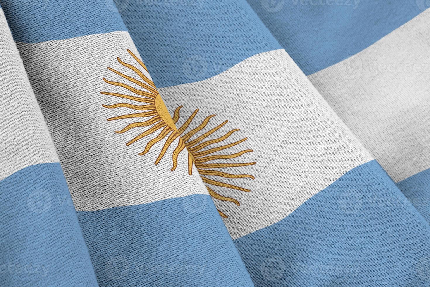 bandeira da argentina com grandes dobras acenando de perto sob a luz do estúdio dentro de casa. os símbolos oficiais e cores no banner foto