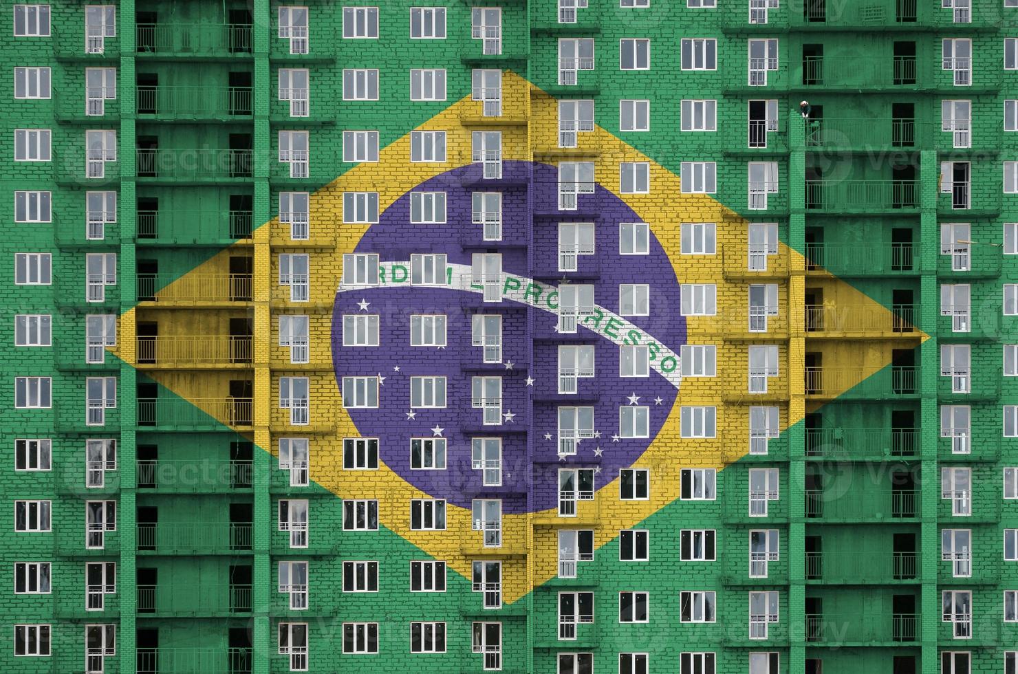 bandeira do brasil retratada em cores de tinta em prédio residencial de vários andares em construção. banner texturizado no fundo da parede de tijolos foto