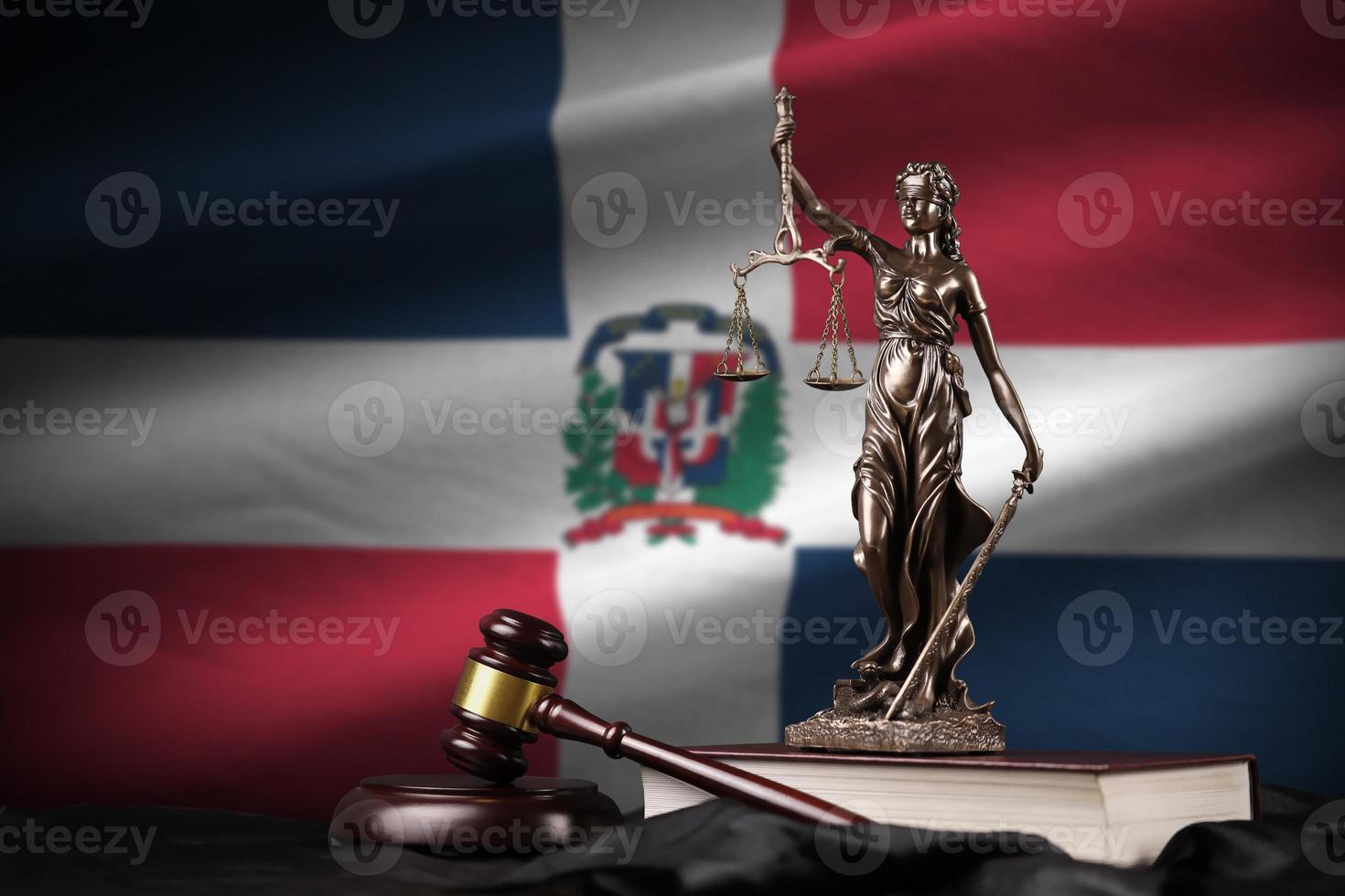 bandeira da república dominicana com a estátua da senhora justiça, constituição e juiz martelo na cortina preta. conceito de julgamento e culpa foto