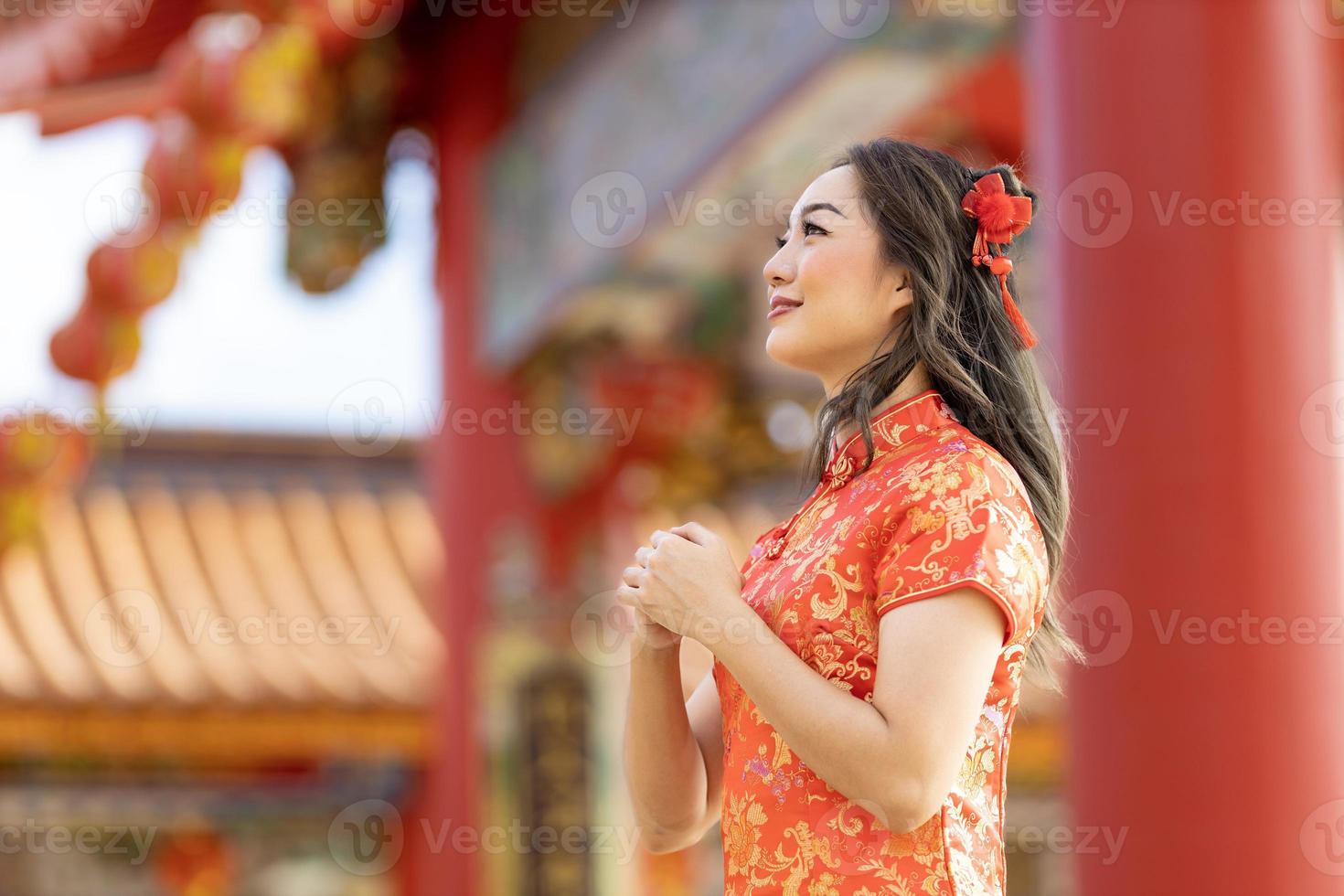 mulher asiática em vestido cheongsam qipao vermelho está fazendo um desejo ao deus ancestral dentro do templo budista chinês durante o ano novo lunar para a bênção dos melhores desejos e o conceito de boa sorte foto