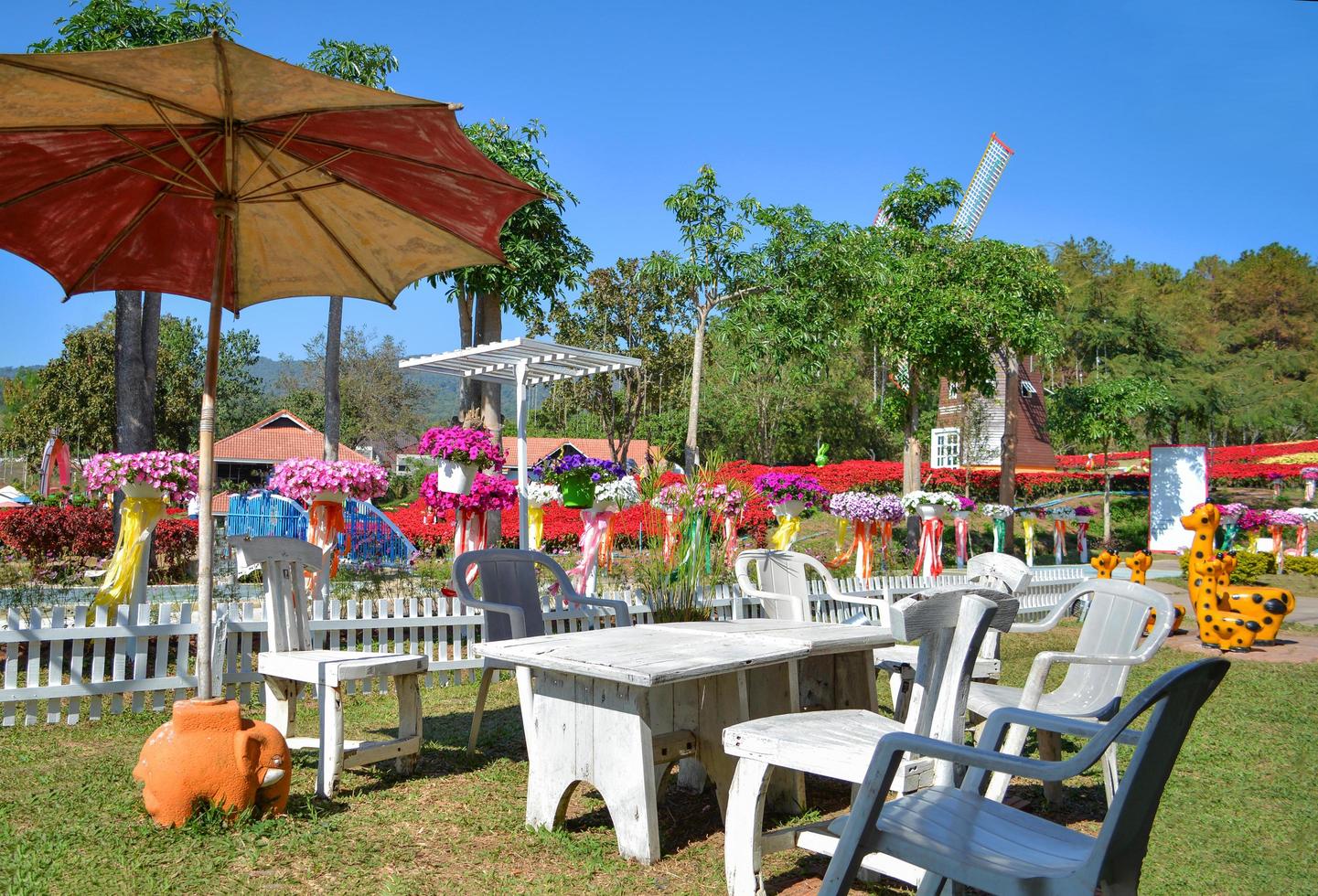 belo jardim com buquê de flores flor colorida em dia brilhante e conjunto de mesa de jantar foto